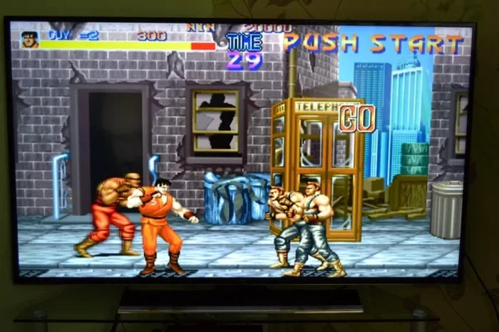Two players playing 90s arcade games on a living room 4K TV with wireless controllers