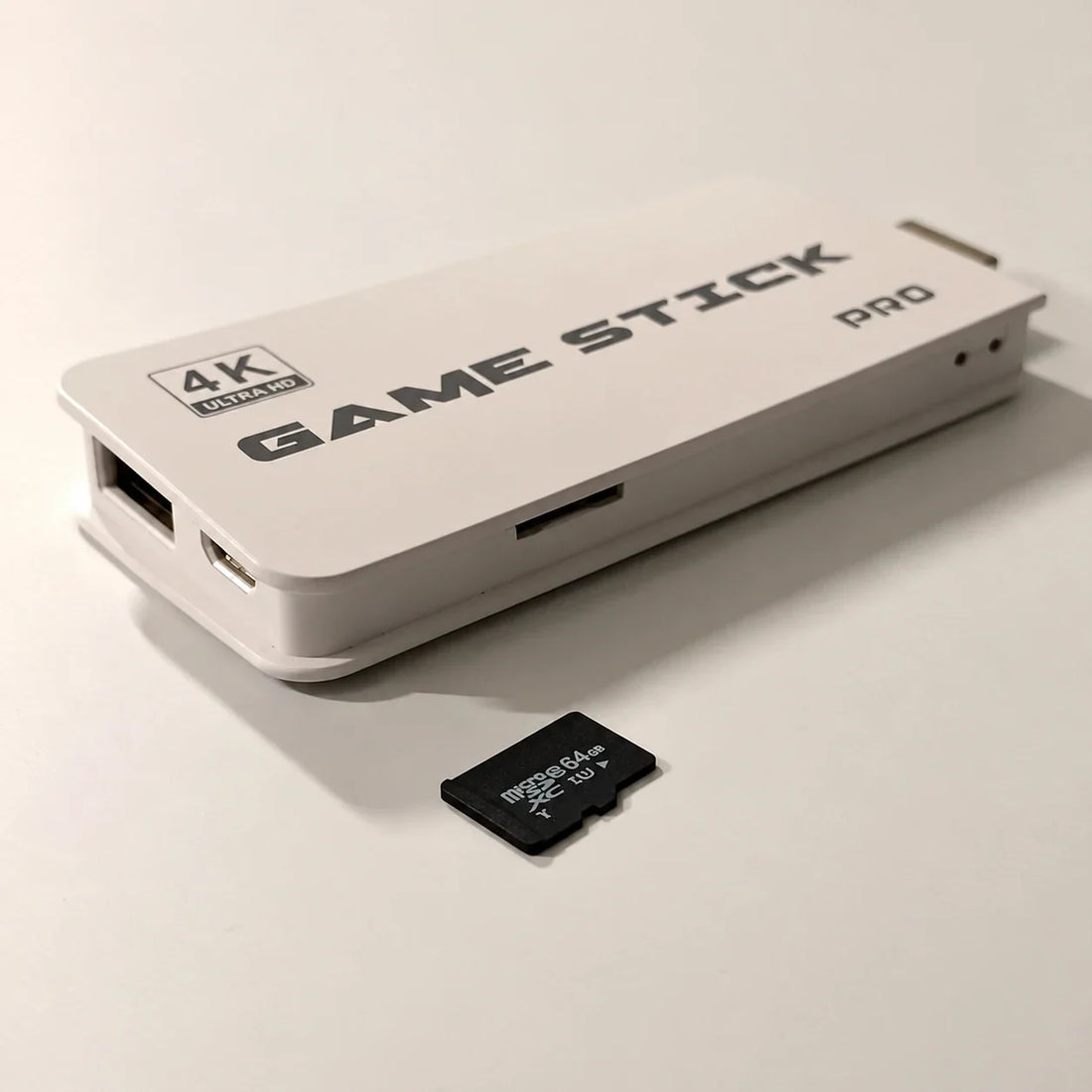 White 4K Ultra HD Game Stick Pro HDMI console showing its side TF card slot next to a 64GB microSDXC memory card