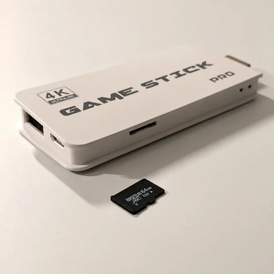 White 4K Ultra HD Game Stick Pro HDMI console showing its side TF card slot next to a 64GB microSDXC memory card
