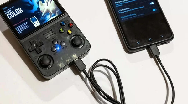 R36S handheld console connected to a 5V USB-A to USB-C charging cable in its left DC port