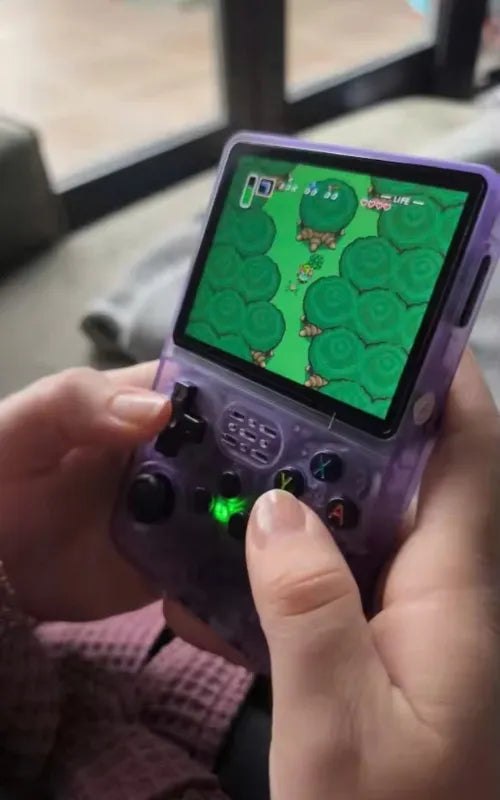 Brett O'Connor's hand holding a purple handheld gaming device with a game displayed on the screen.