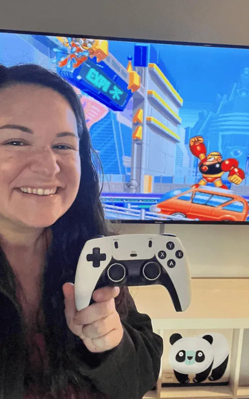 Bec Louise holding a gaming controller in front of a screen displaying a retro video game.
