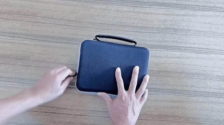 Person opening a black carrying case on a wooden surface